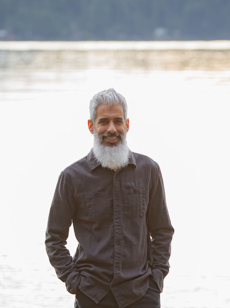 Cyrus Jagosh smiling outdoors near the water, hands in his pockets