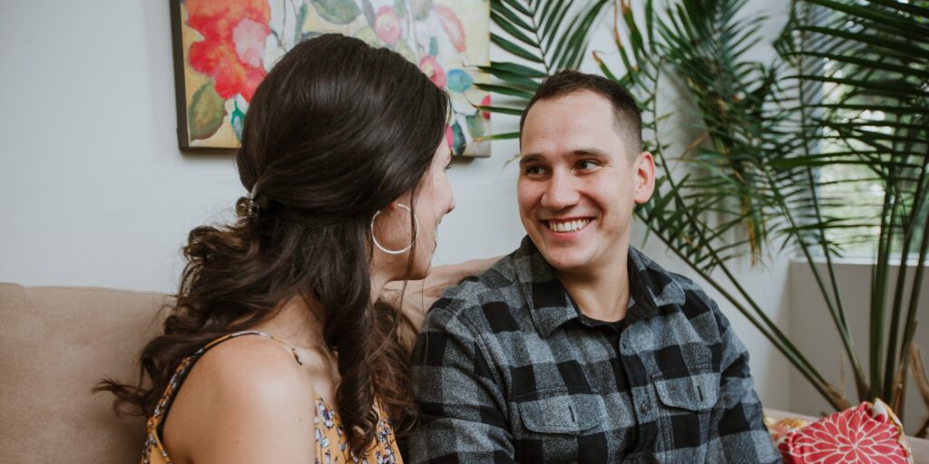 Couple in conversation, smiling, in a warm living room setting — couples therapy in Vancouver, BC