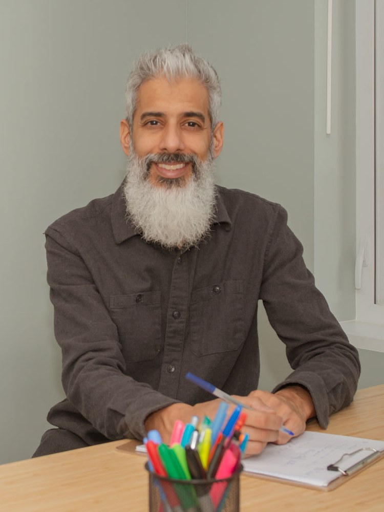 Cyrus Jagosh, Registered Therapeutic Counsellor, taking notes at his desk in Vancouver, BC