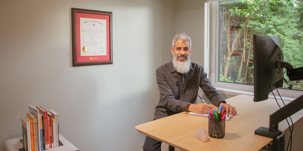 Cyrus Jagosh, Registered Therapeutic Counsellor, writing at his desk during individual therapy work in Vancouver, BC