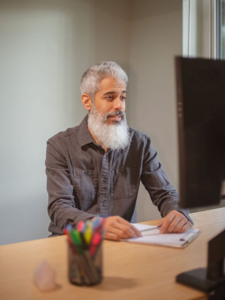 Cyrus Jagosh, online counsellor in Vancouver, seated at his desk during a session.